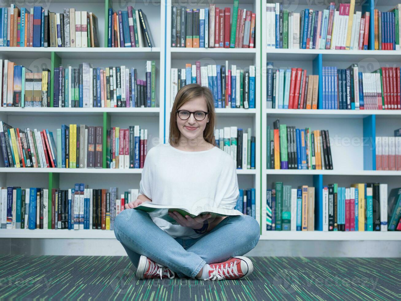 étudiant fille en train de lire livre dans bibliothèque photo