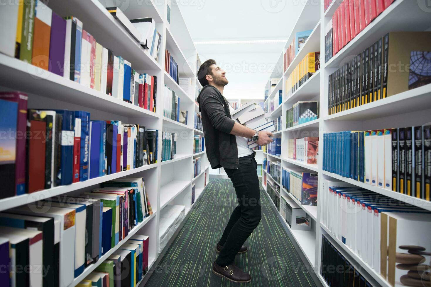 étudiant tenant beaucoup de livres dans la bibliothèque de l'école photo