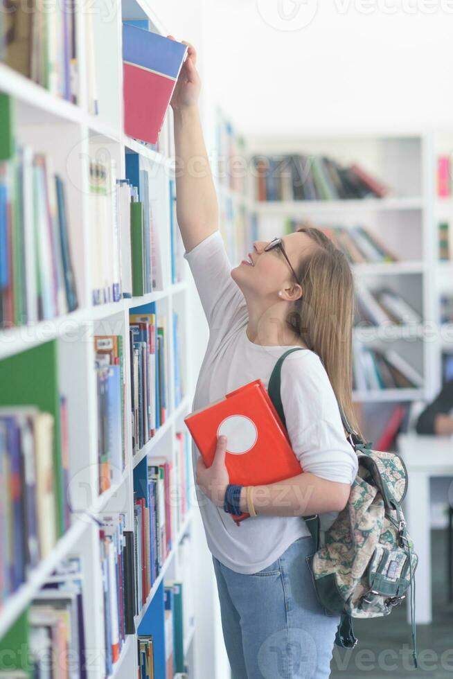étudiante célèbre en sélectionnant un livre à lire dans la bibliothèque photo