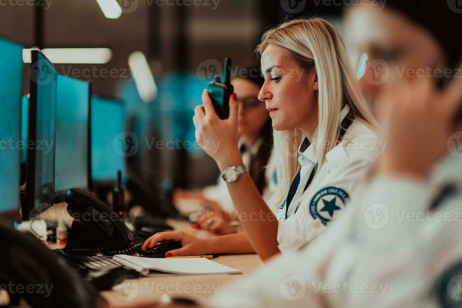 femelle Sécurité opérateur en portant portable radio dans main tandis que travail dans une Les données système contrôle pièce des bureaux technique opérateur travail à poste de travail avec plusieurs affiche, Sécurité garde travail sur photo