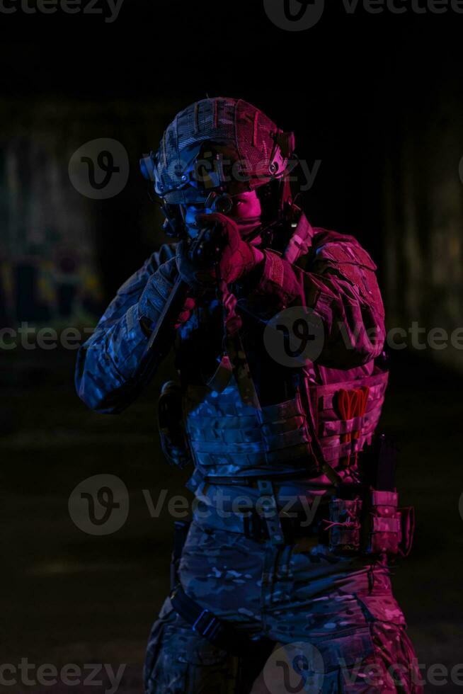 armée soldat dans combat uniformes avec un agression fusil et combat casque nuit mission foncé Contexte. bleu et violet gel lumière effet. photo