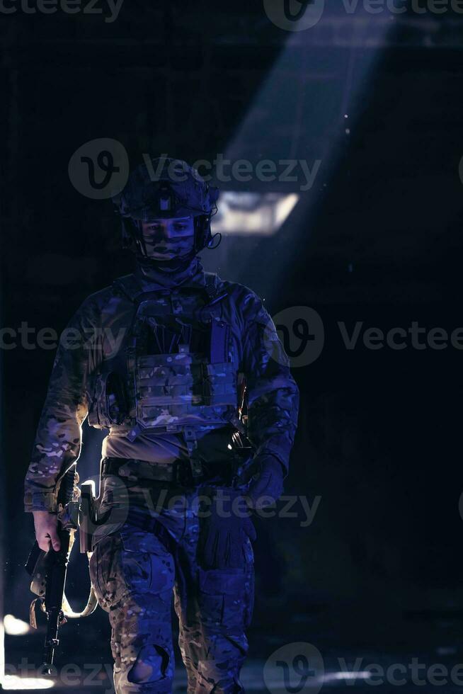 armée soldat dans combat uniformes avec un agression fusil et combat casque nuit mission foncé Contexte. bleu et violet gel lumière effet. photo