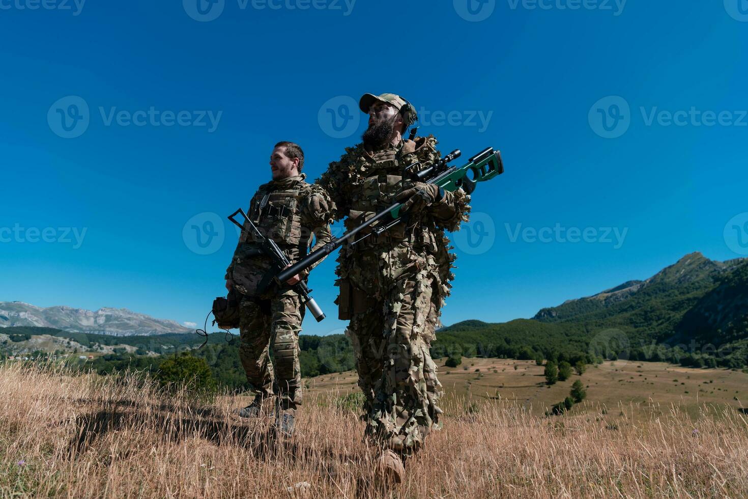 une tireur d'élite équipe équipe de soldats est Aller à l'abri. tireur d'élite assistant et équipe chef en marchant et visée dans la nature avec Jaune herbe et bleu ciel. tactique camouflage uniforme. photo