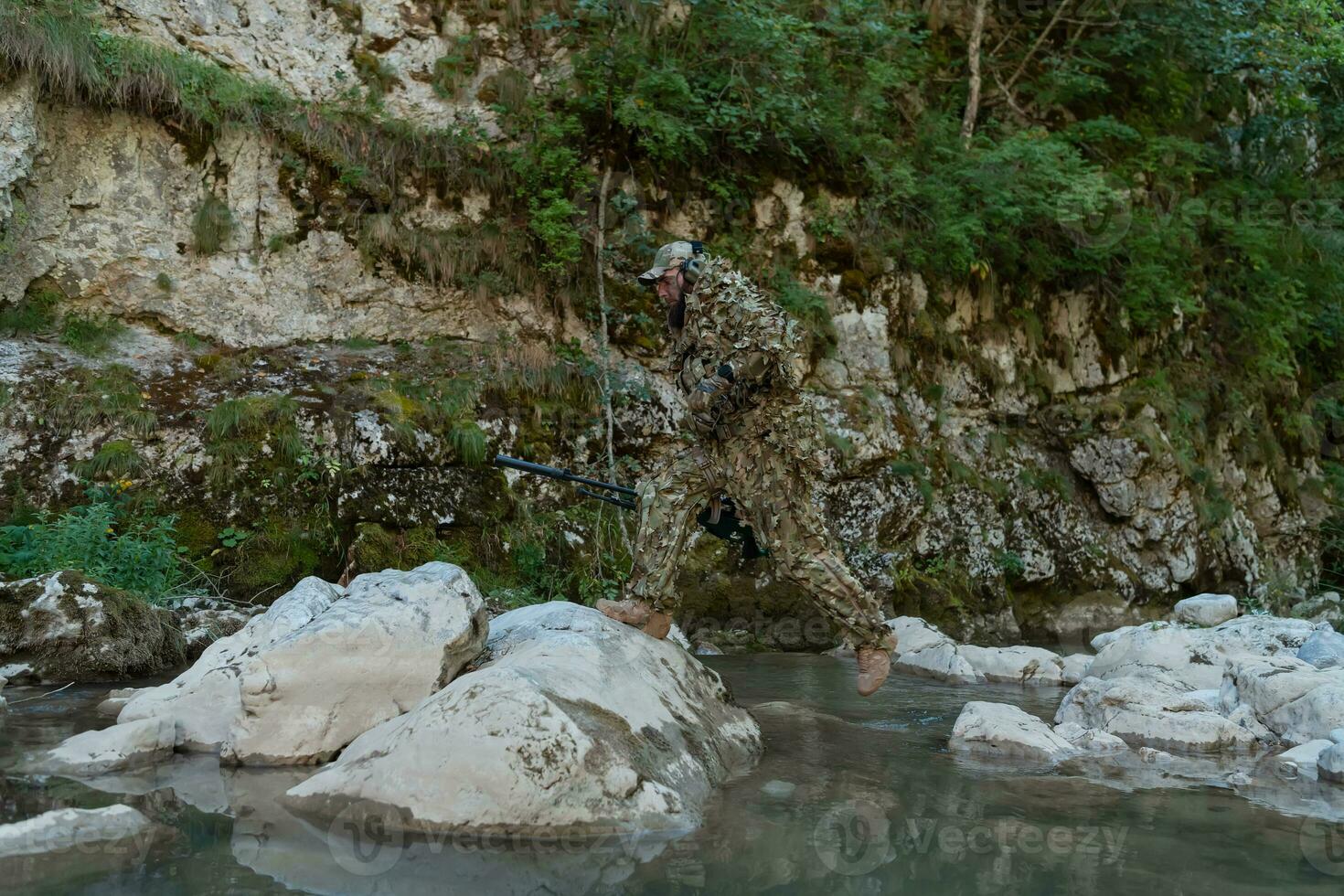 une militaire homme ou airsoft joueur dans une camouflage costume se faufiler le rivière et objectifs de une tireur d'élite fusil à le côté ou à cible. photo