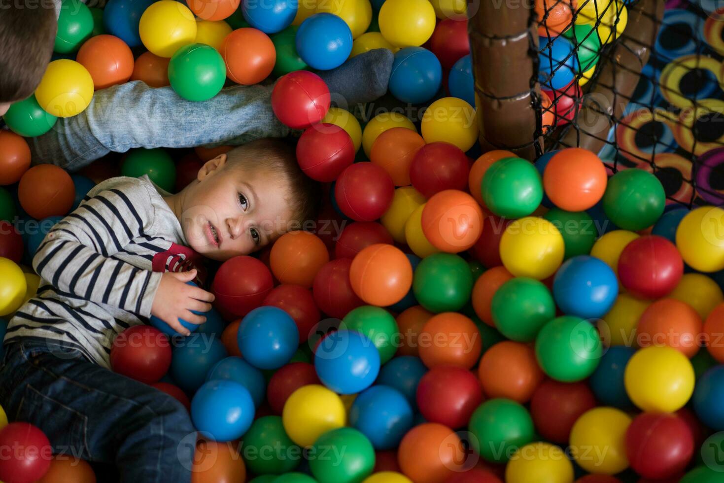 garçon ayant amusement dans des centaines de coloré Plastique des balles photo