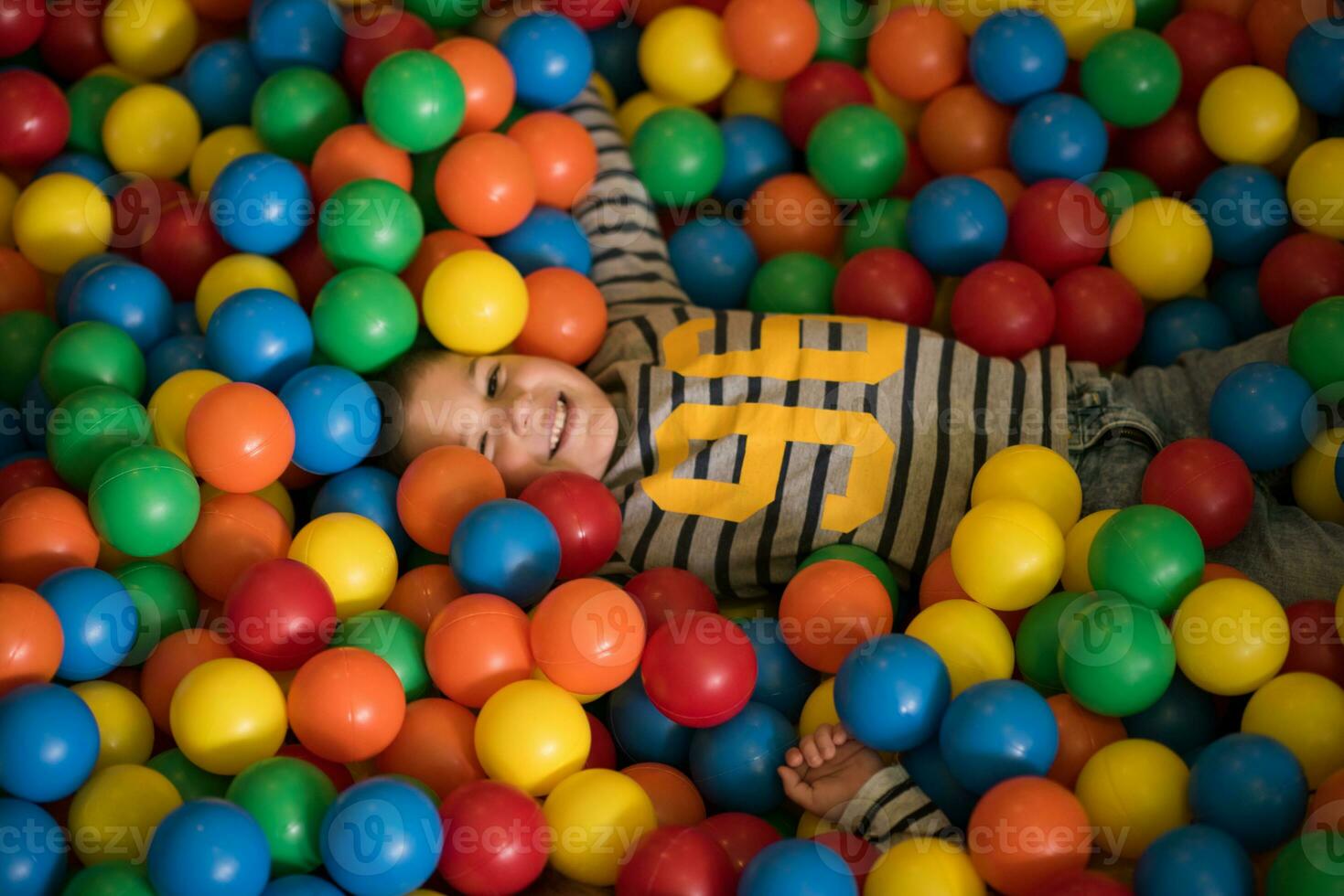 garçon ayant amusement dans des centaines de coloré Plastique des balles photo