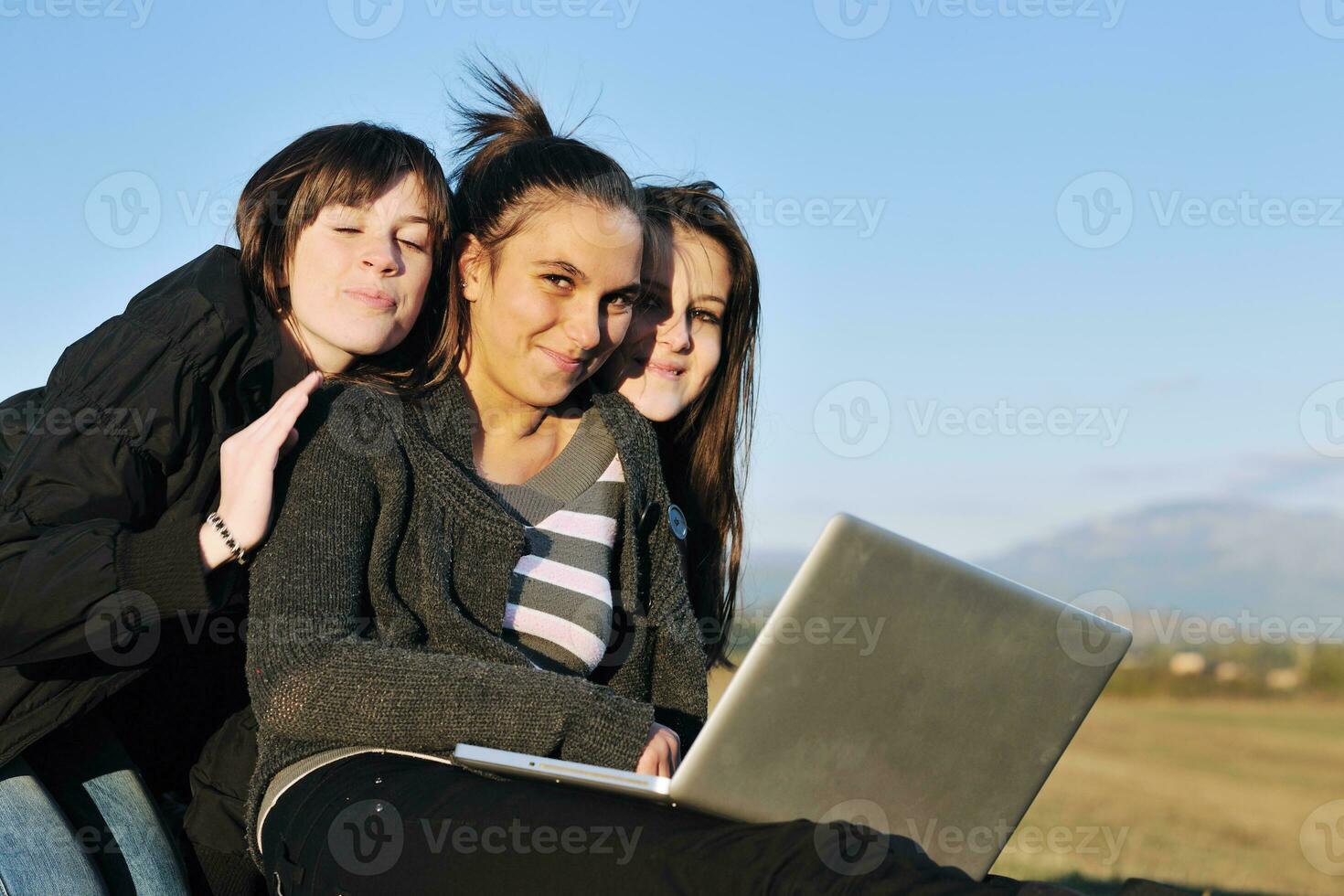 groupe d'adolescents travaillant sur un ordinateur portable en plein air photo