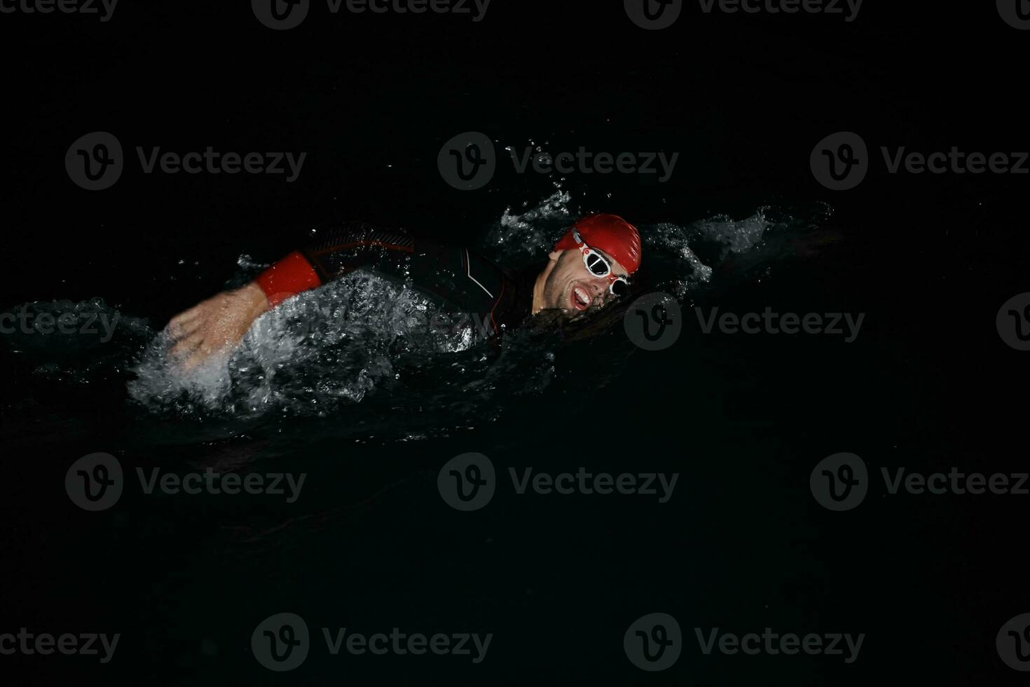 athlète de triathlon nageant dans la nuit noire portant une combinaison de plongée photo