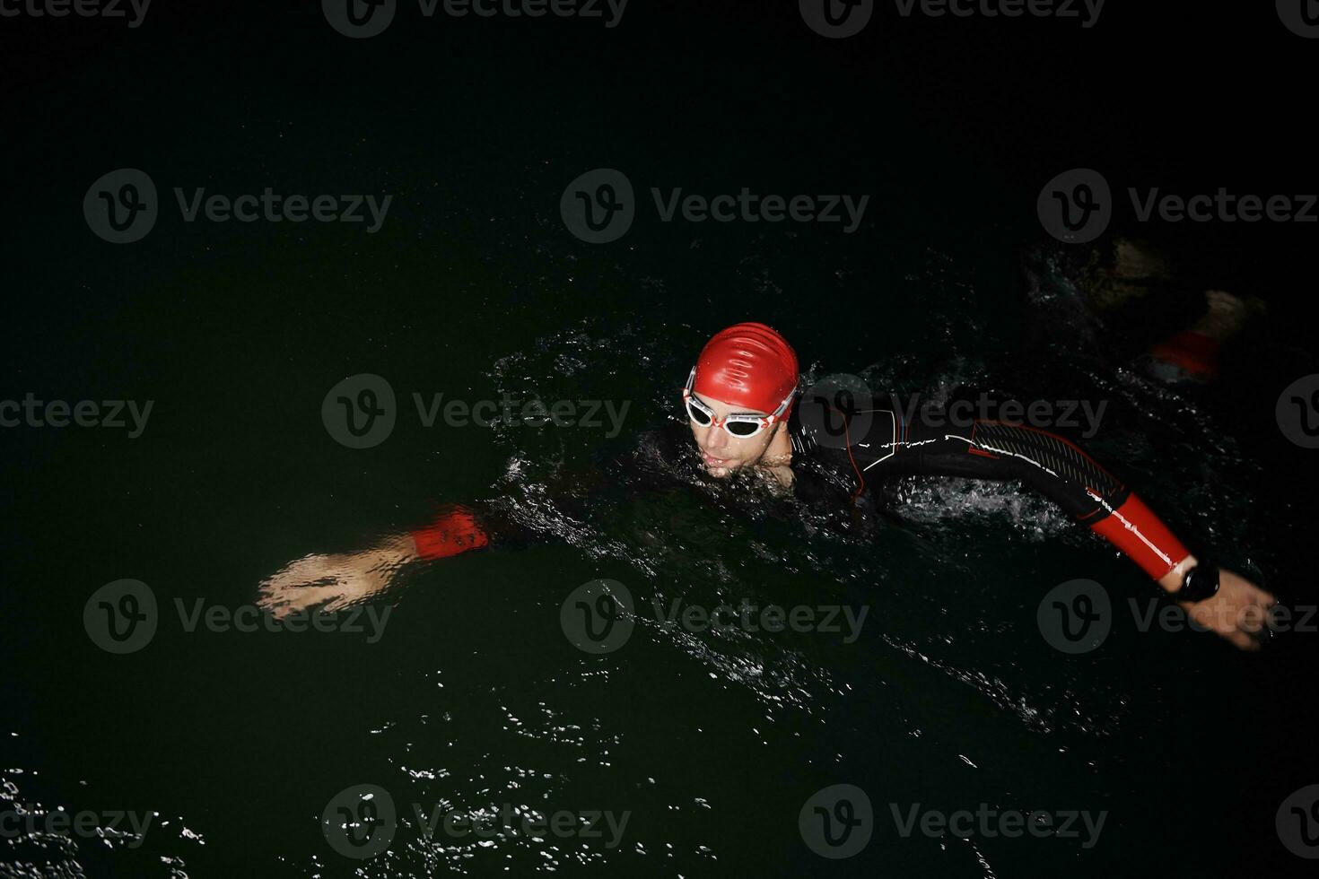 athlète de triathlon nageant dans la nuit noire portant une combinaison de plongée photo