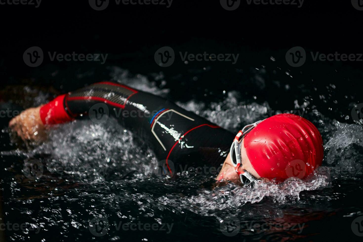 athlète de triathlon nageant dans la nuit noire portant une combinaison de plongée photo