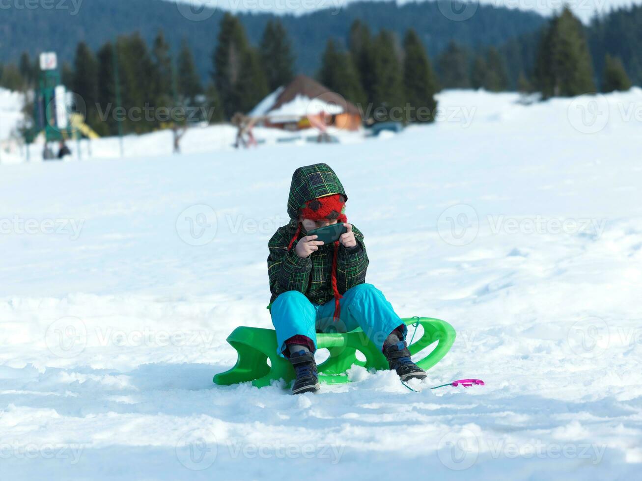 Jeune garçon avoir amusement sur hiver vacances et jouer Jeux sur téléphone photo