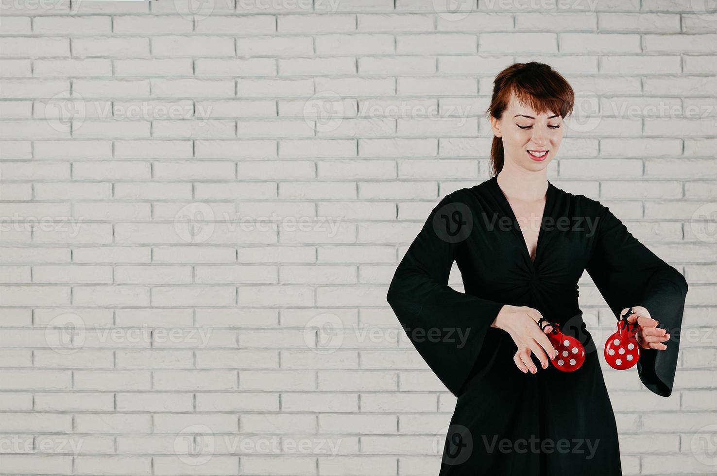 jeune femme séduisante en robe noire, danse, castagnettes rouges, souriante photo