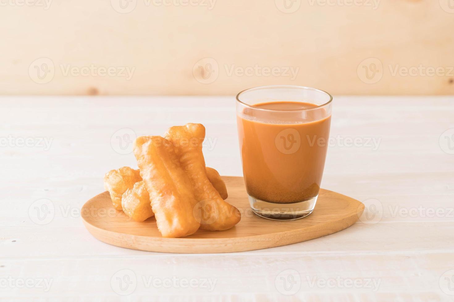 bâton de pâte frit avec du thé au lait sur bois photo