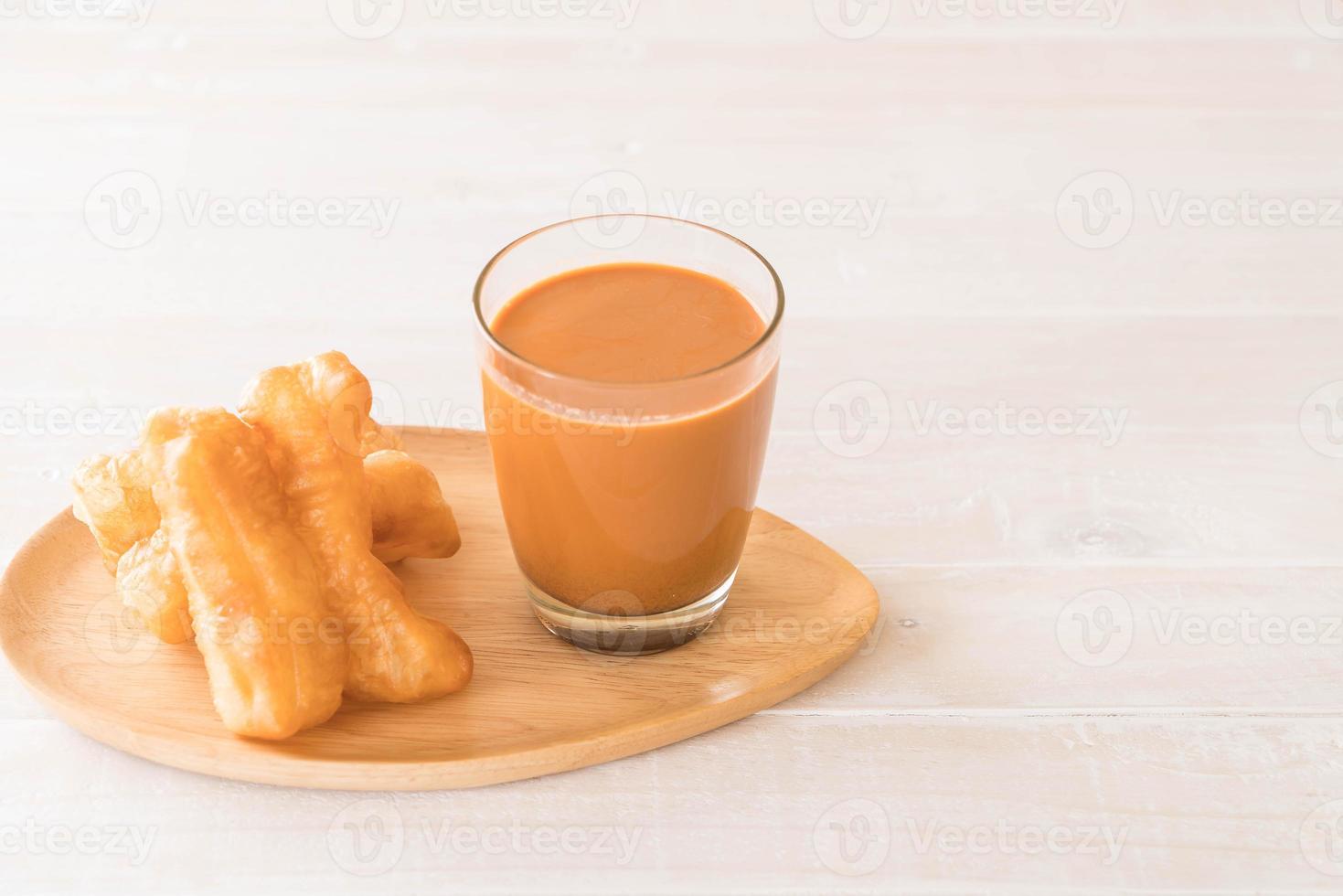 bâton de pâte frit avec du thé au lait sur bois photo