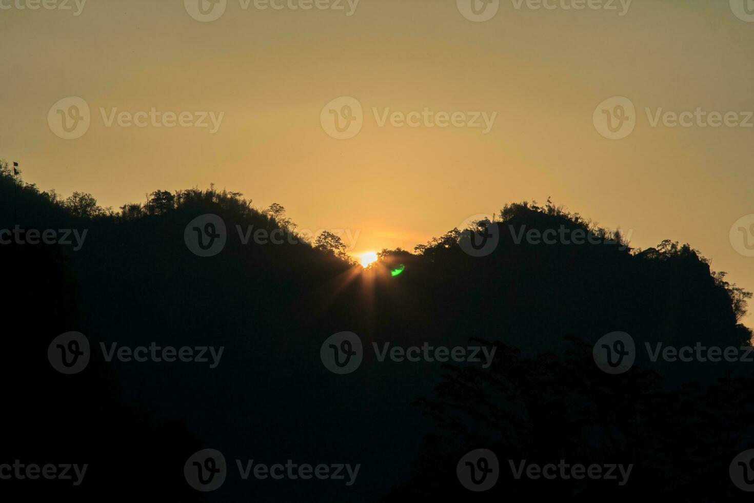 le soleil se lève et se couche le matin et le soir et les arbres sont ombragés de noir - ciel orange et nuages. chaleureux, romantique et magnifiquement beau, il a l'air chaleureux et voyageur. photo