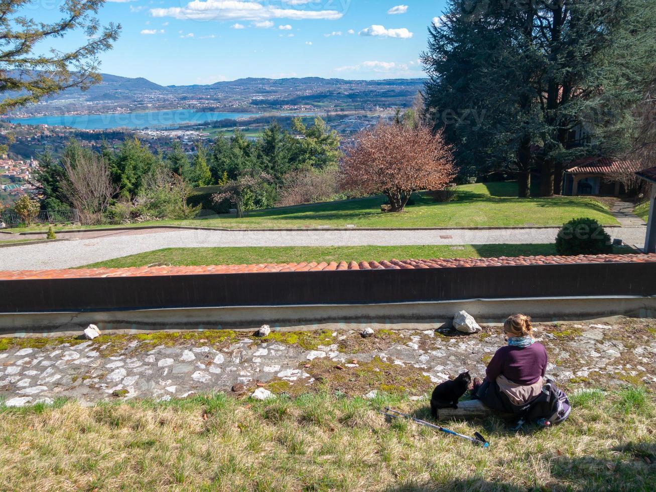 femme et chat sur l'herbe dans les alpes, panorama sur le lac, village photo