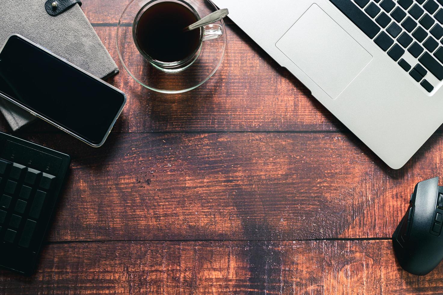 tasse à café, ordinateur portable, livre, téléphone intelligent au bureau. photo