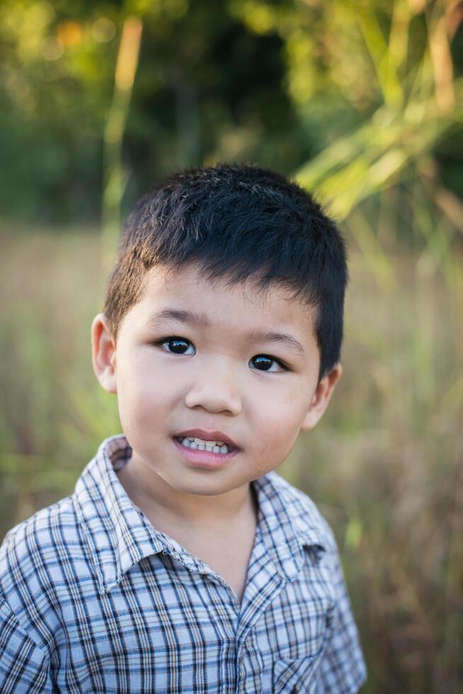 gros plan d'un garçon asiatique mignon jouant et souriant à l'extérieur. photo