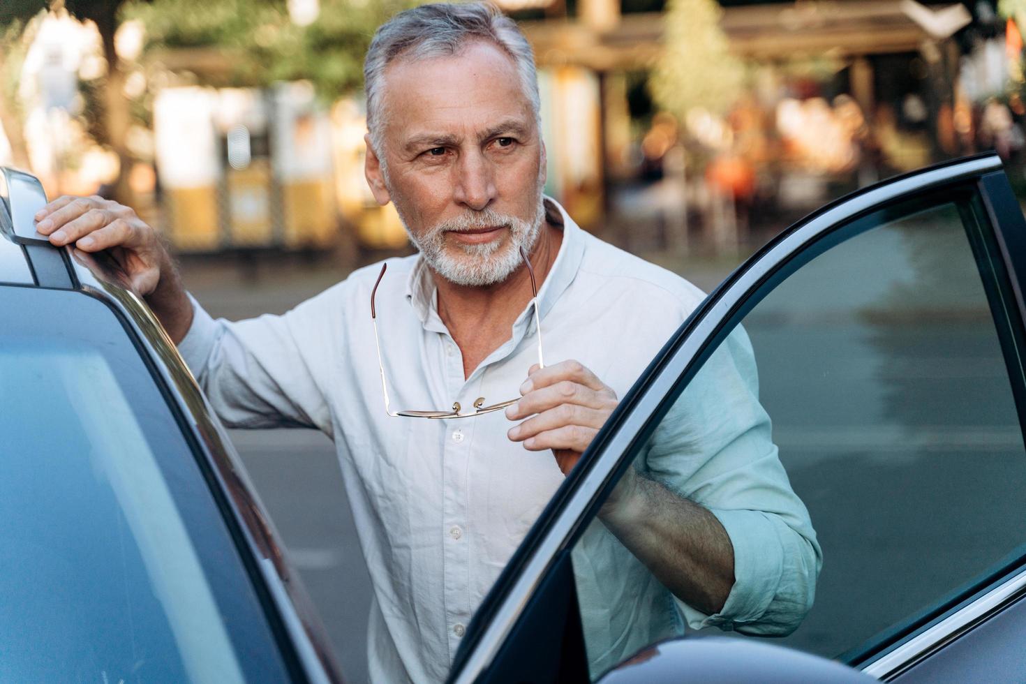 un homme âgé se tient près de son suv de location photo