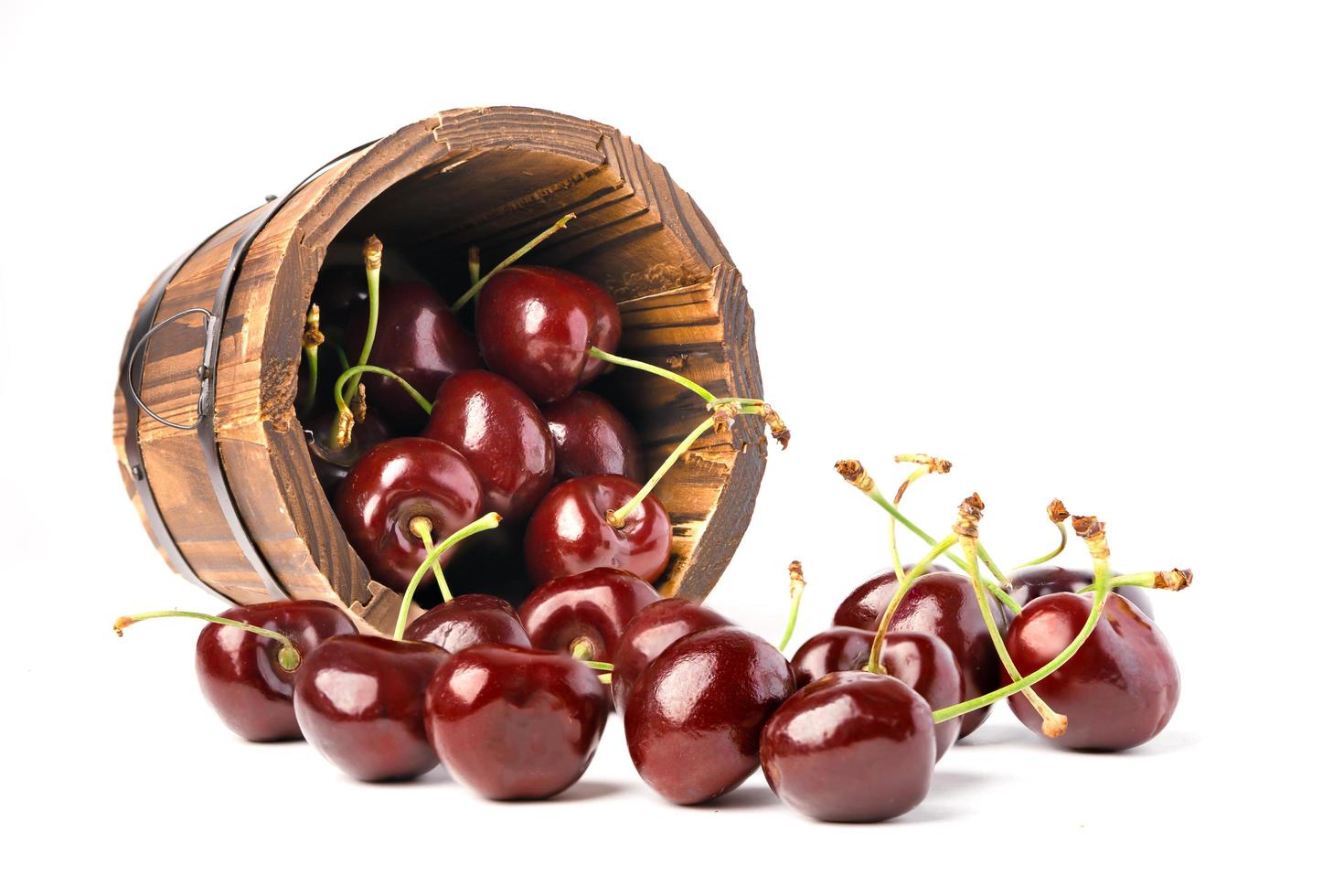 berry cerise dans un pot de baril rond en bois sur fond blanc. photo