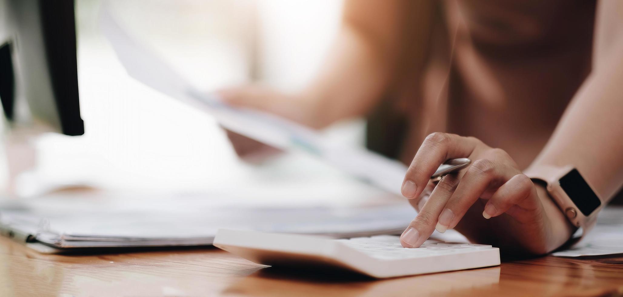 gros plan femme utilisant une calculatrice et un ordinateur portable pour faire des mathématiques photo