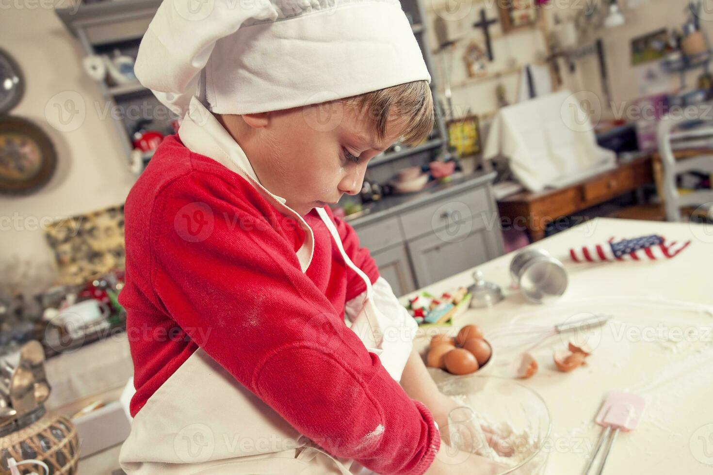 mignonne enfant dans le cuisine tandis que mélange le pâte photo