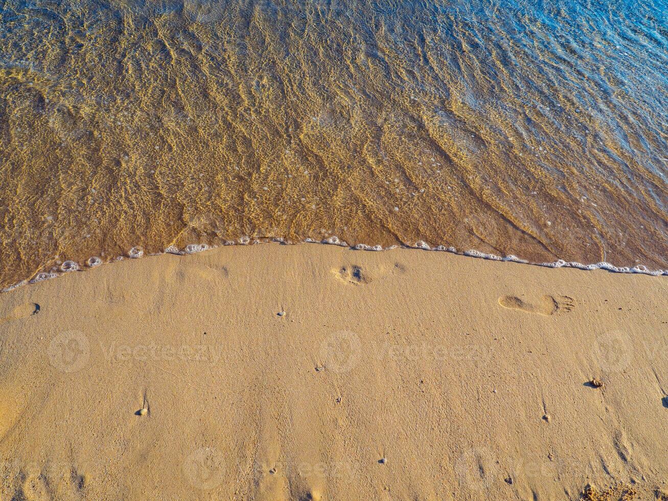 petit vague la lessive une façon empreintes dans le le sable - sur le plage photo