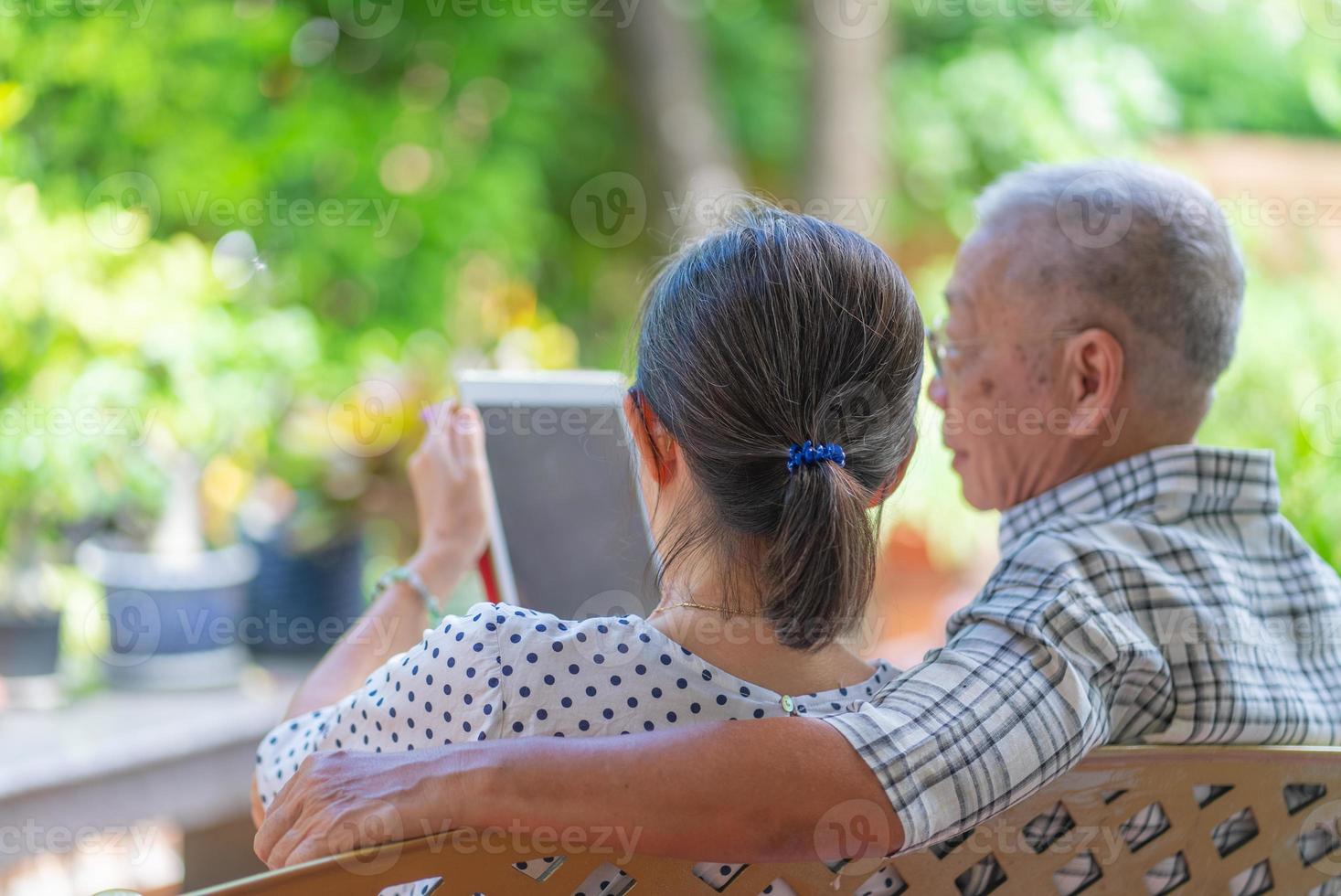 couple asiatique âgé utilisant une tablette pour lire les médias sociaux ensemble à la maison photo