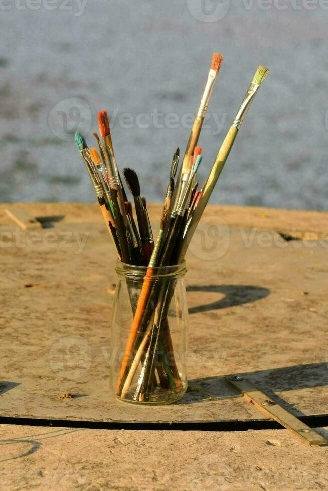 une vase rempli avec peindre brosses séance sur une table photo