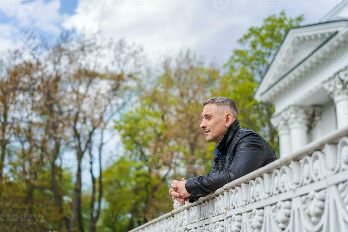 une homme dans décontractée vêtements des stands près une magnifique bâtiment et regards dans le distance photo