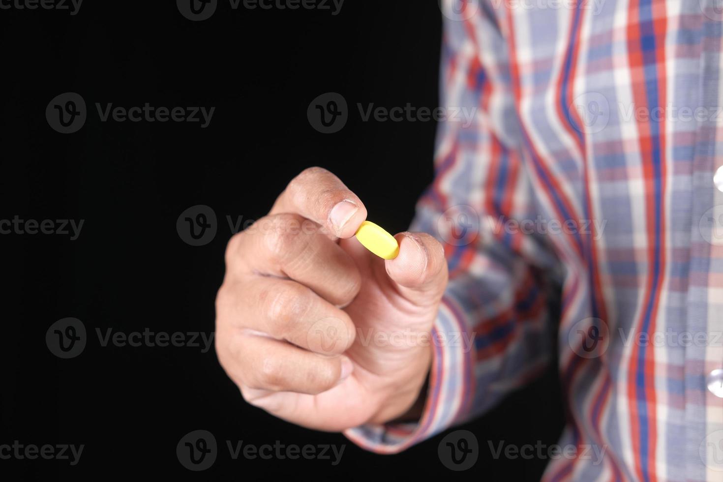 Jeune homme hand holding medical pills isolated on black photo