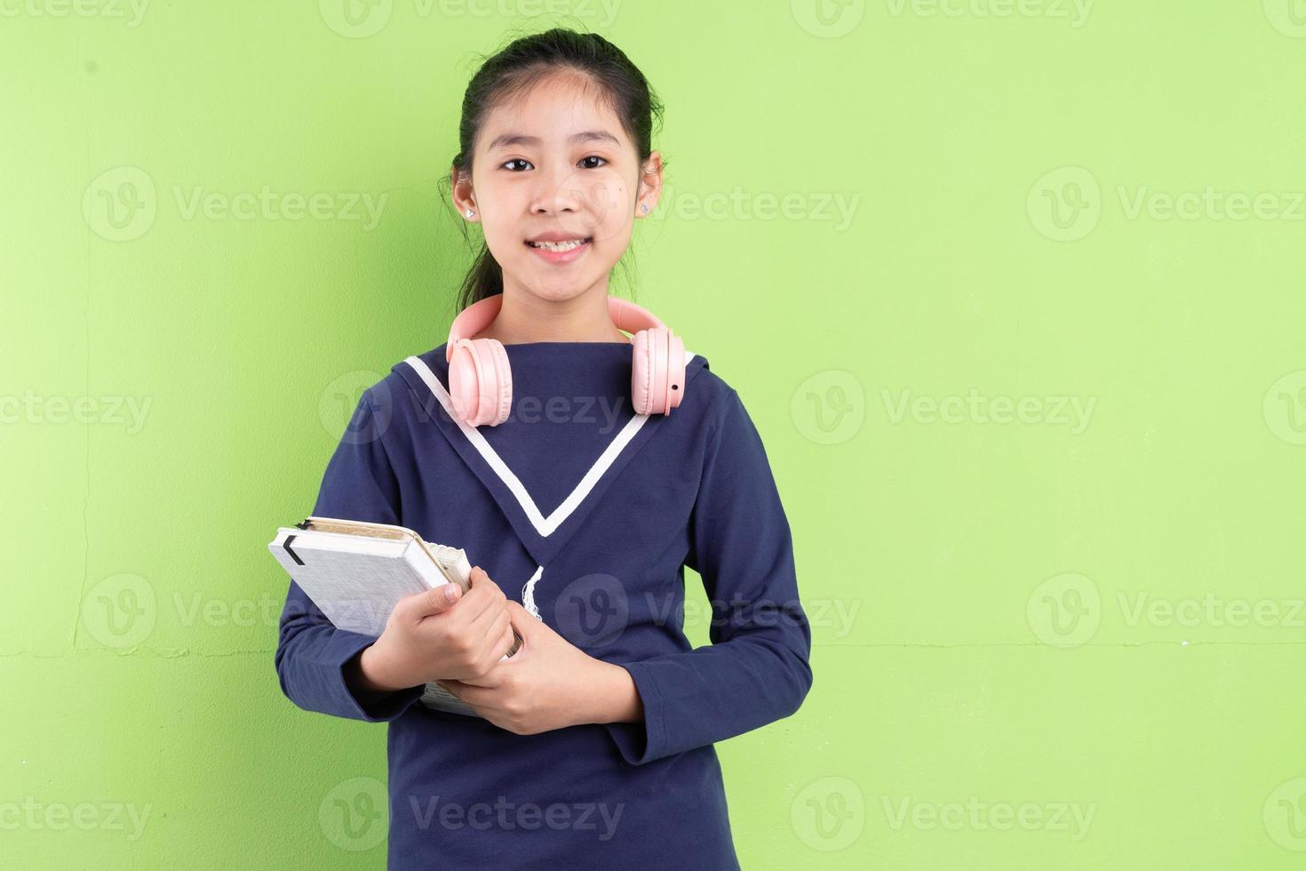 Portrait d'enfant asiatique tenant un livre sur bkacground vert photo