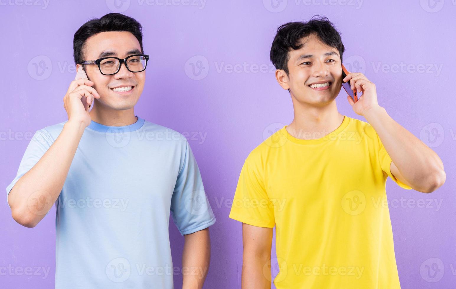 deux frères asiatiques utilisant des téléphones portables sur fond violet photo