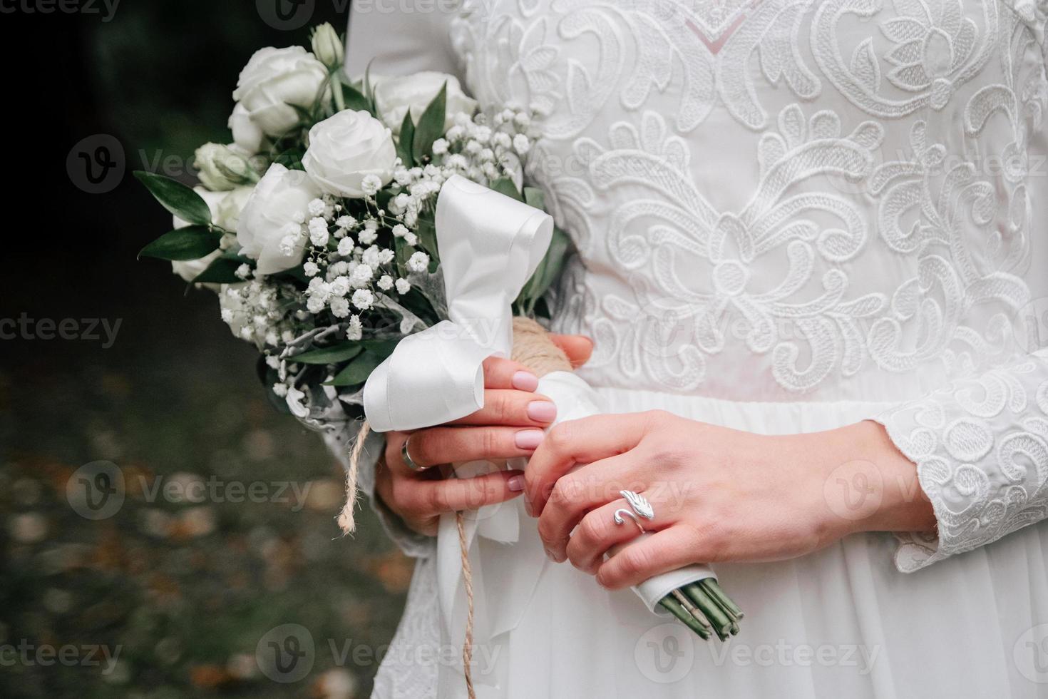 bouquet de mariage de fleurs roses blanches dans les mains de la mariée photo