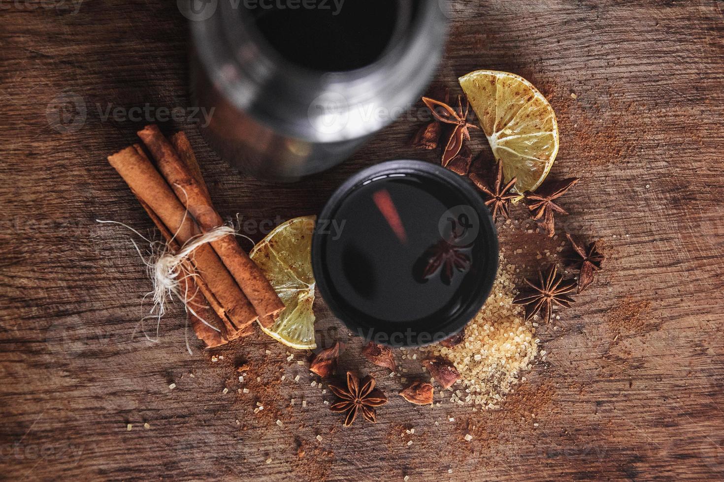 vin chaud dans une tasse avec des espèces parfumées sur une planche en bois rustique photo