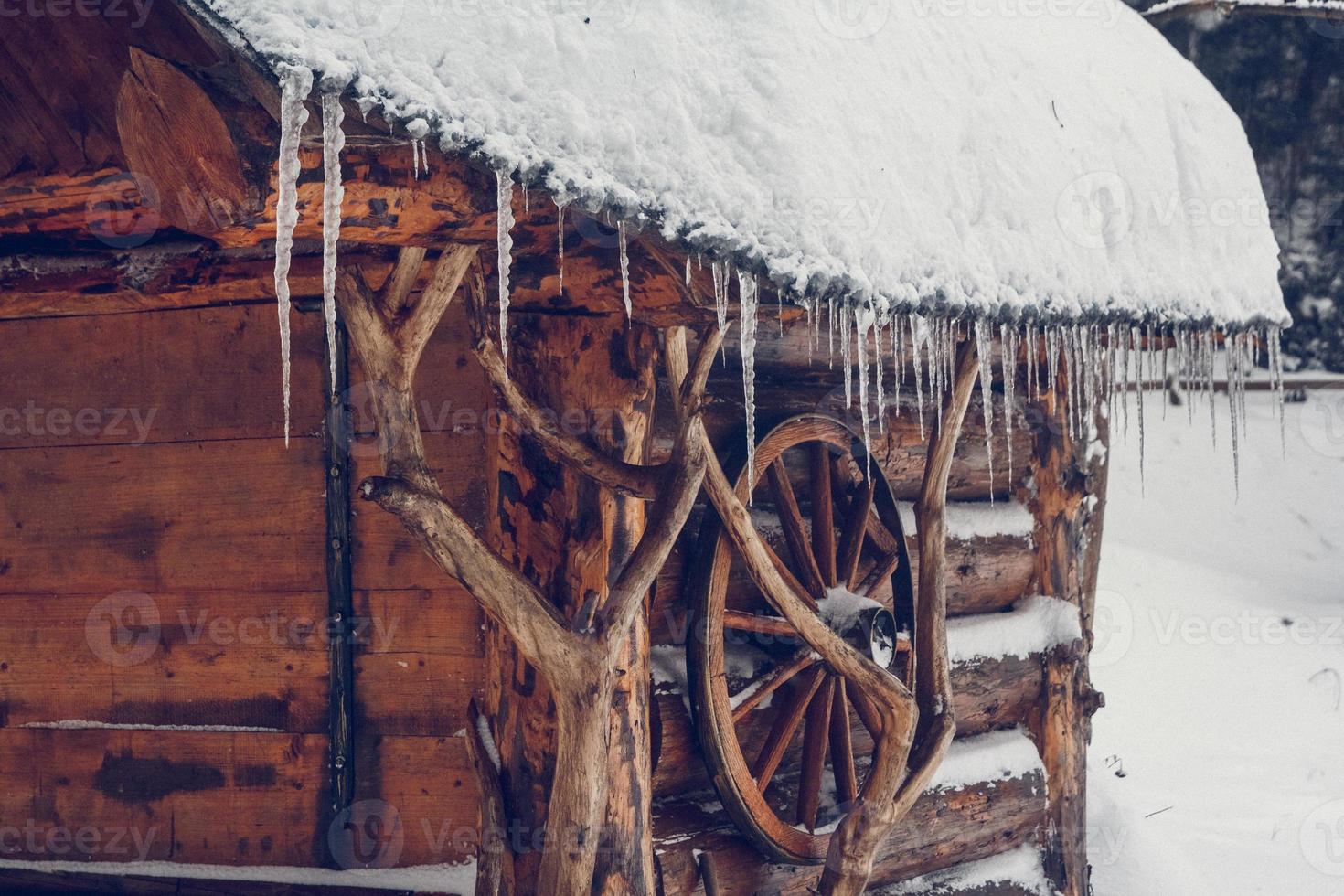 les glaçons pendent du toit d'une maison en bois photo