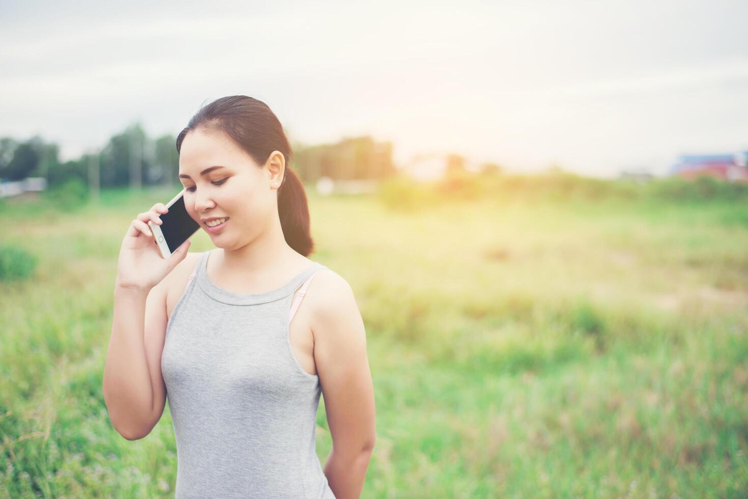 belle jeune femme utilisant un smartphone et souriant dans le parc. photo