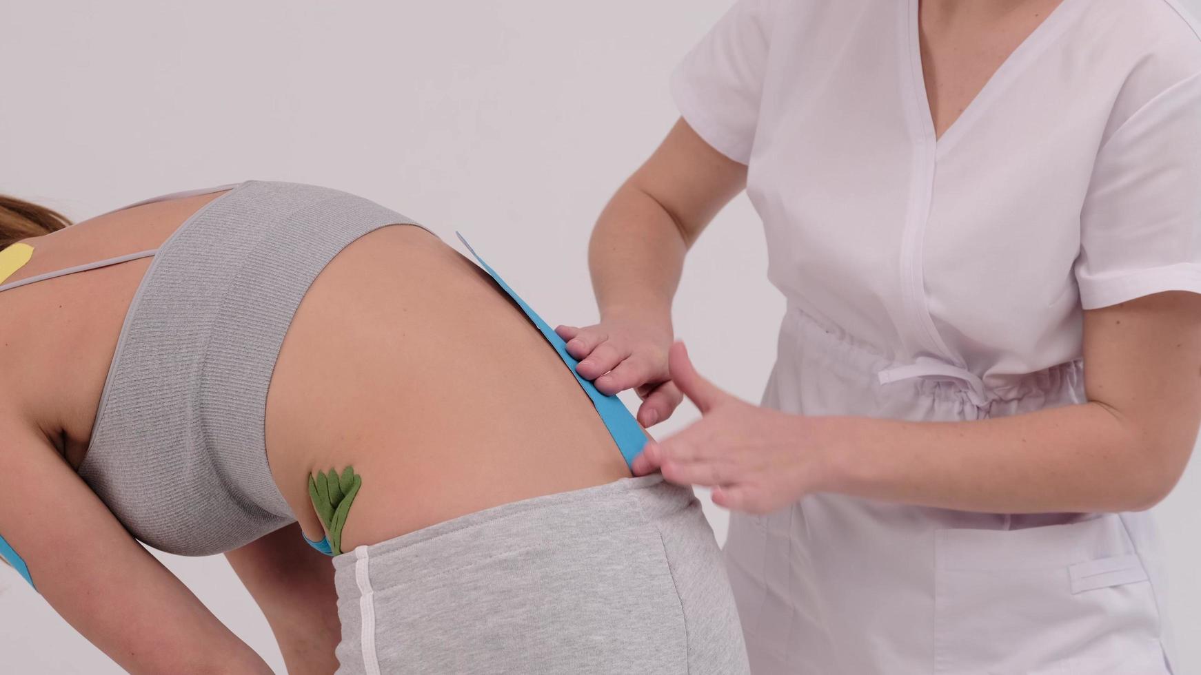 le thérapeute applique du ruban kinesio sur le dos de la femme. physiothérapie, kinésiologie et traitement de récupération. photo