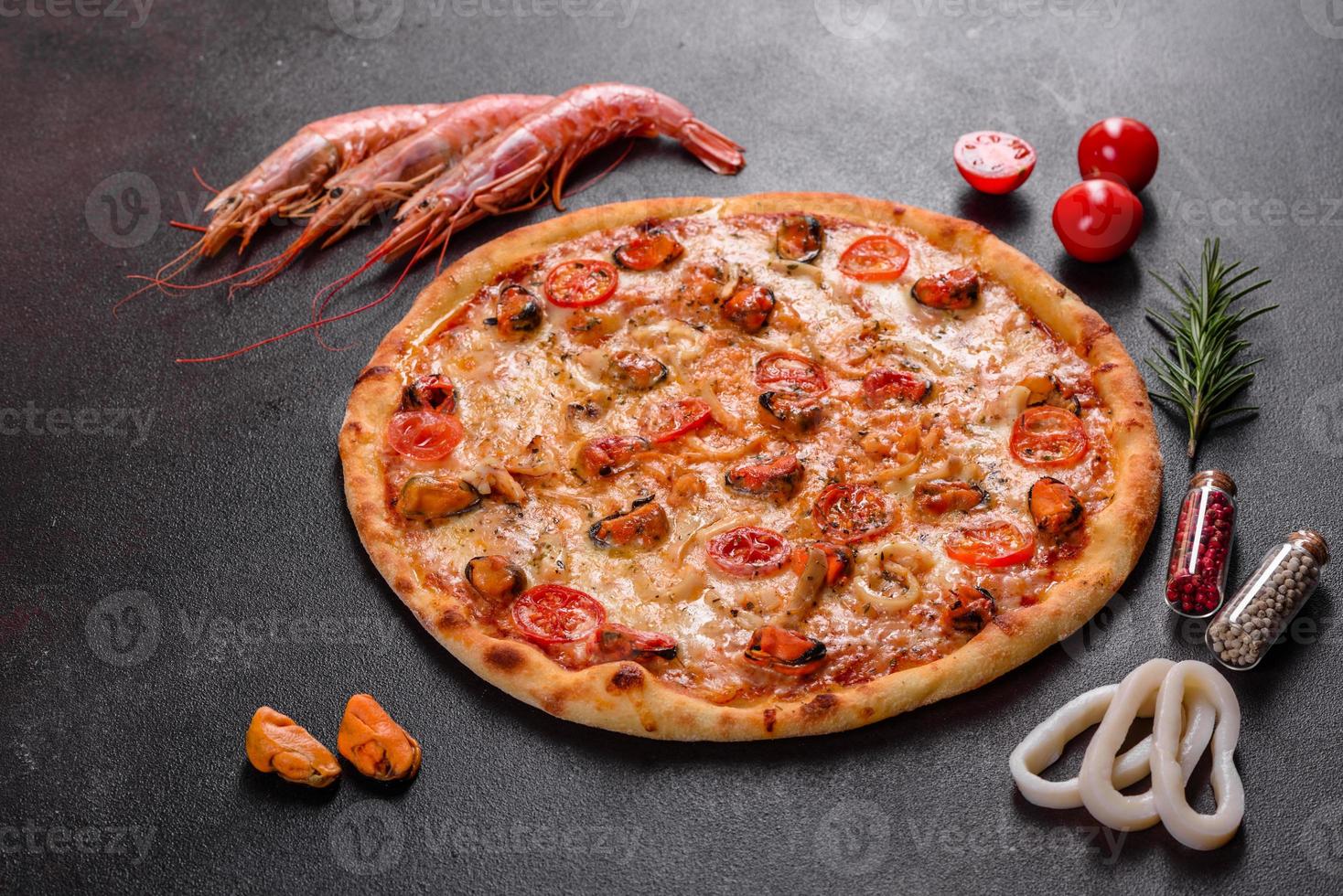 savoureuse pizza en tranches avec fruits de mer et tomate sur fond de béton photo