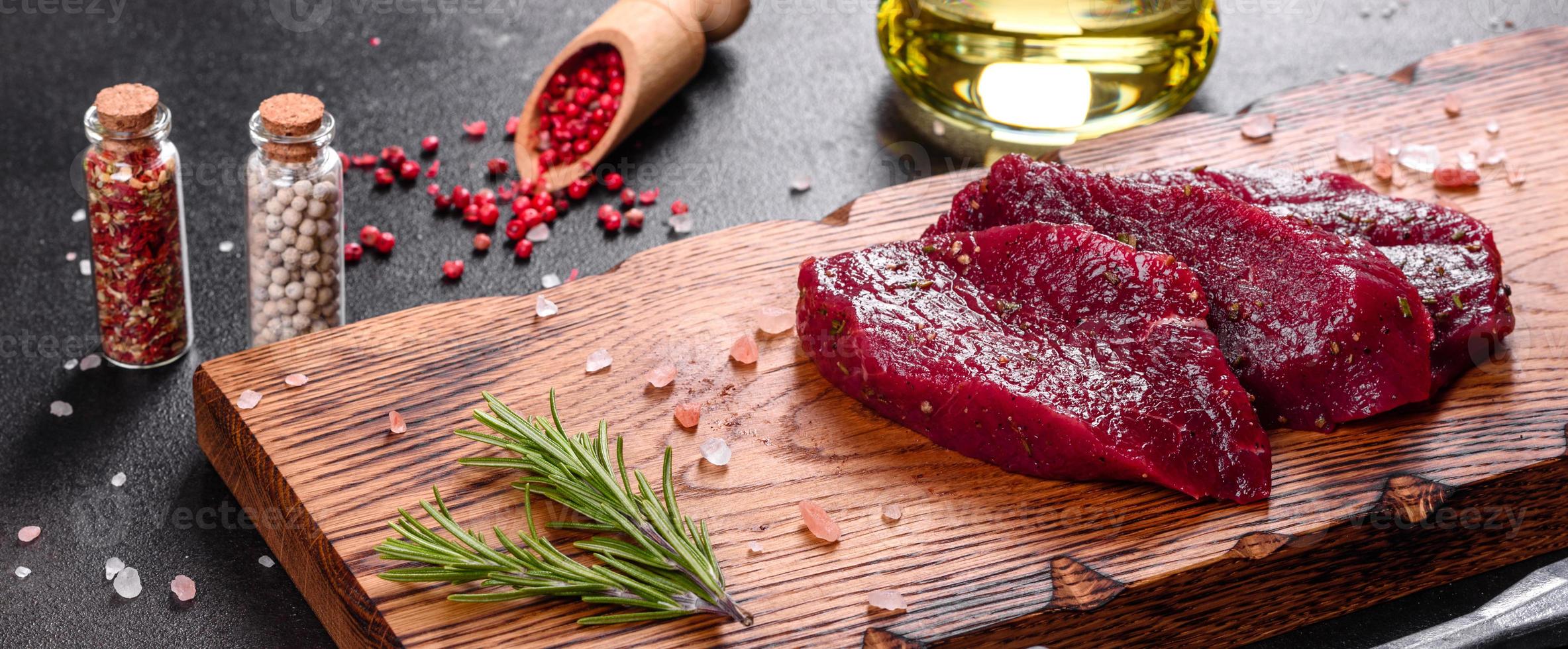 steak mignon de boeuf cru frais, avec sel, grains de poivre, thym, tomates photo