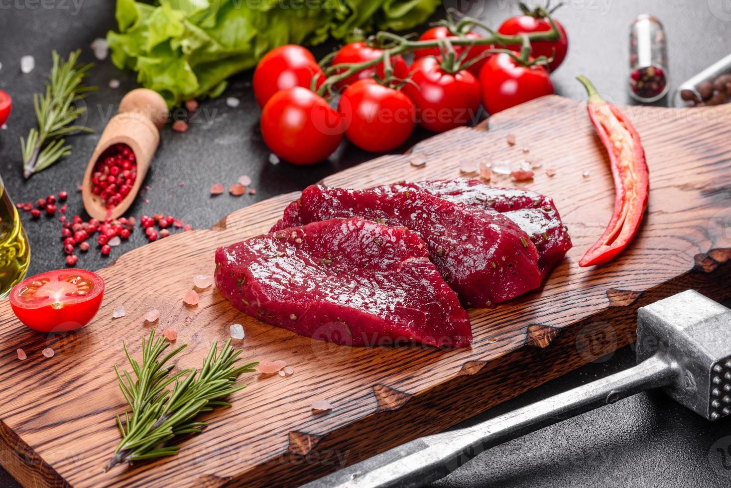 steak mignon de boeuf cru frais, avec sel, grains de poivre, thym, tomates photo