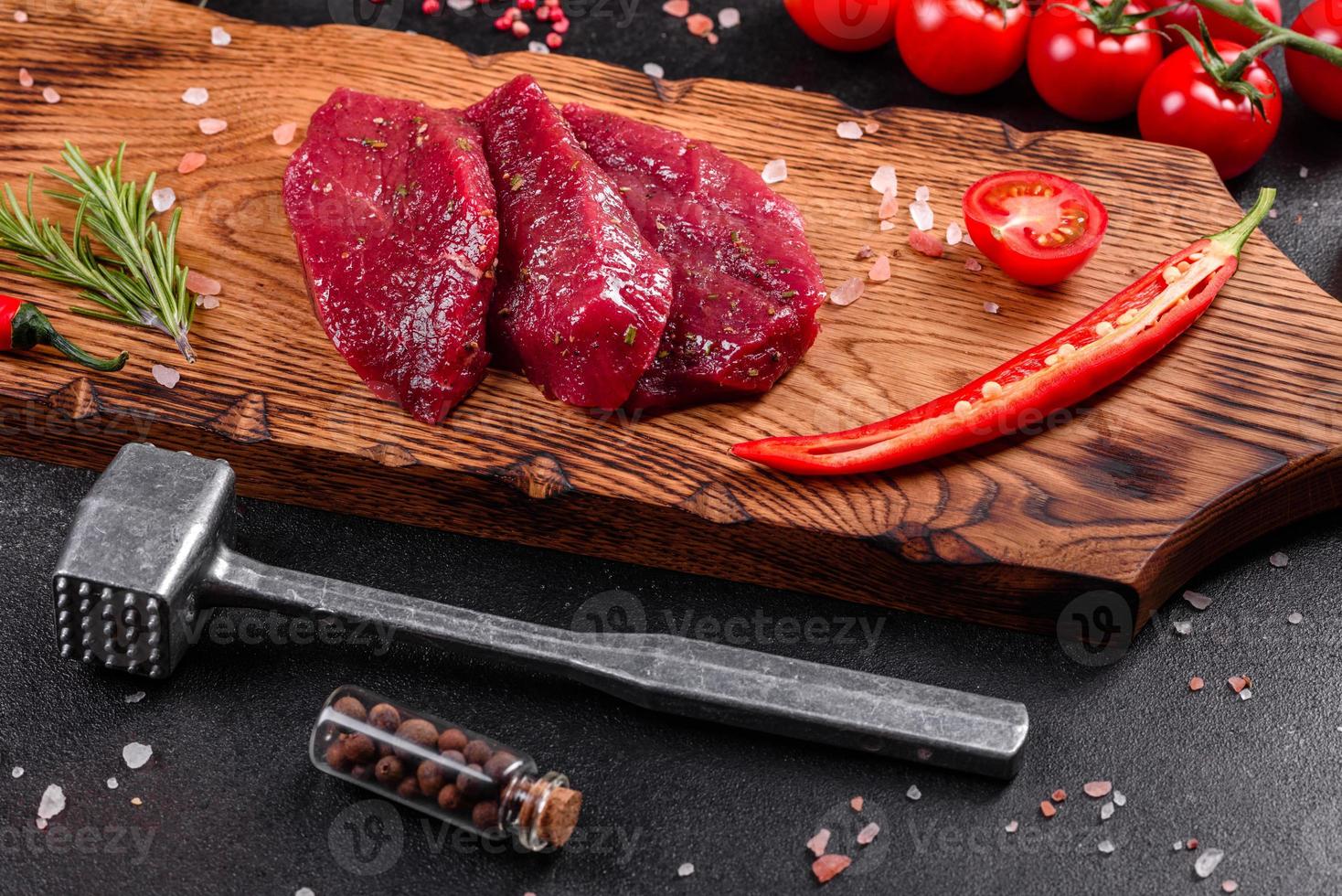 steak mignon de boeuf cru frais, avec sel, grains de poivre, thym, tomates photo