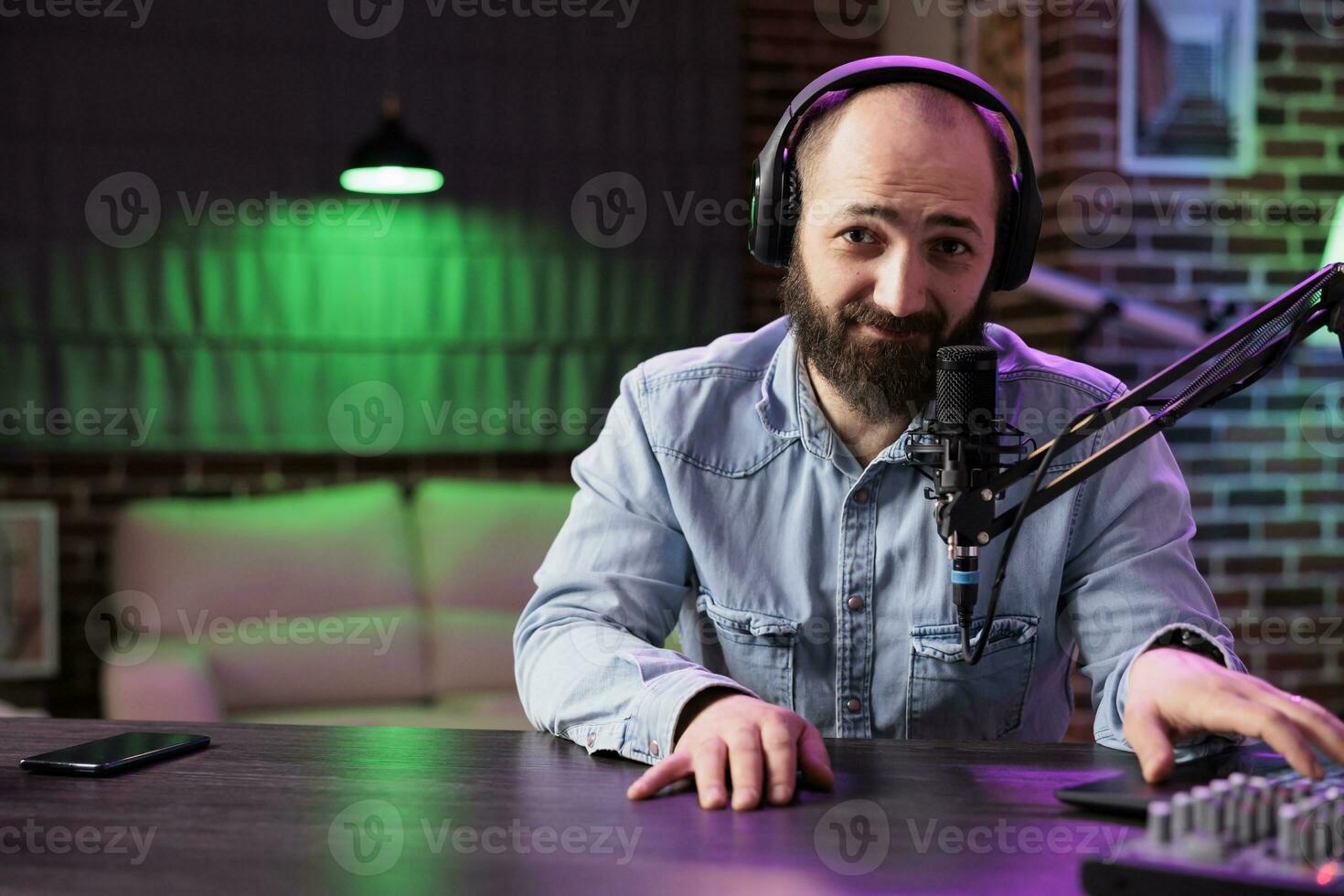 portrait de expert radio hôte en jouant la musique dans professionnel sur air Accueil studio avec néon lumières. dj en utilisant haute qualité installer à produire et distribuer musical pièces, divertissant Ventilateurs photo