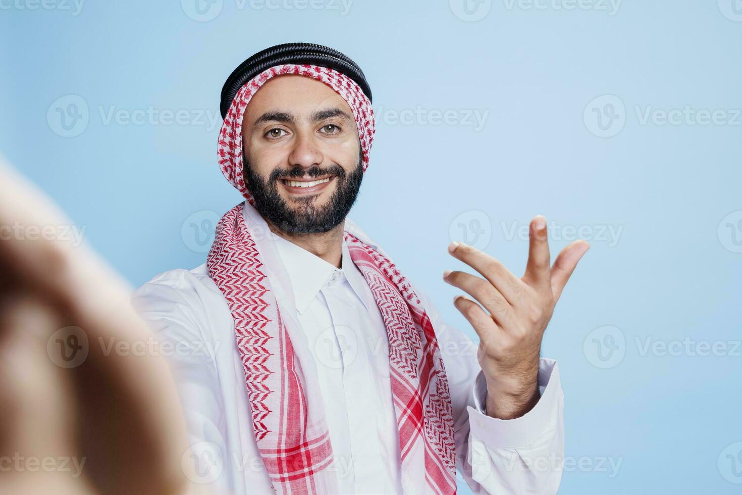 de bonne humeur musulman homme portant traditionnel vêtements engageant dans vidéo appel de pov perspective. souriant arabe la personne dans thobe et foulard à la recherche à de face caméra tandis que Parlant dans en ligne réunion photo