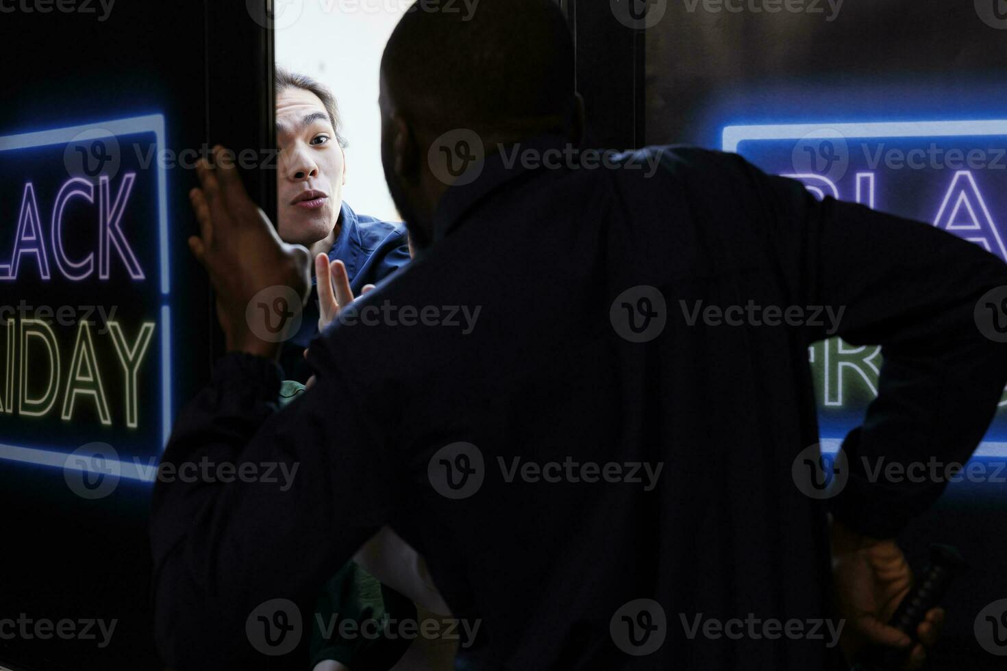 Jeune asiatique gars en essayant à avoir à l'intérieur de vente au détail boutique sur noir Vendredi avant ouverture heures, fou client combat et argumenter avec Sécurité garde tandis que permanent à achats centre commercial entrée photo