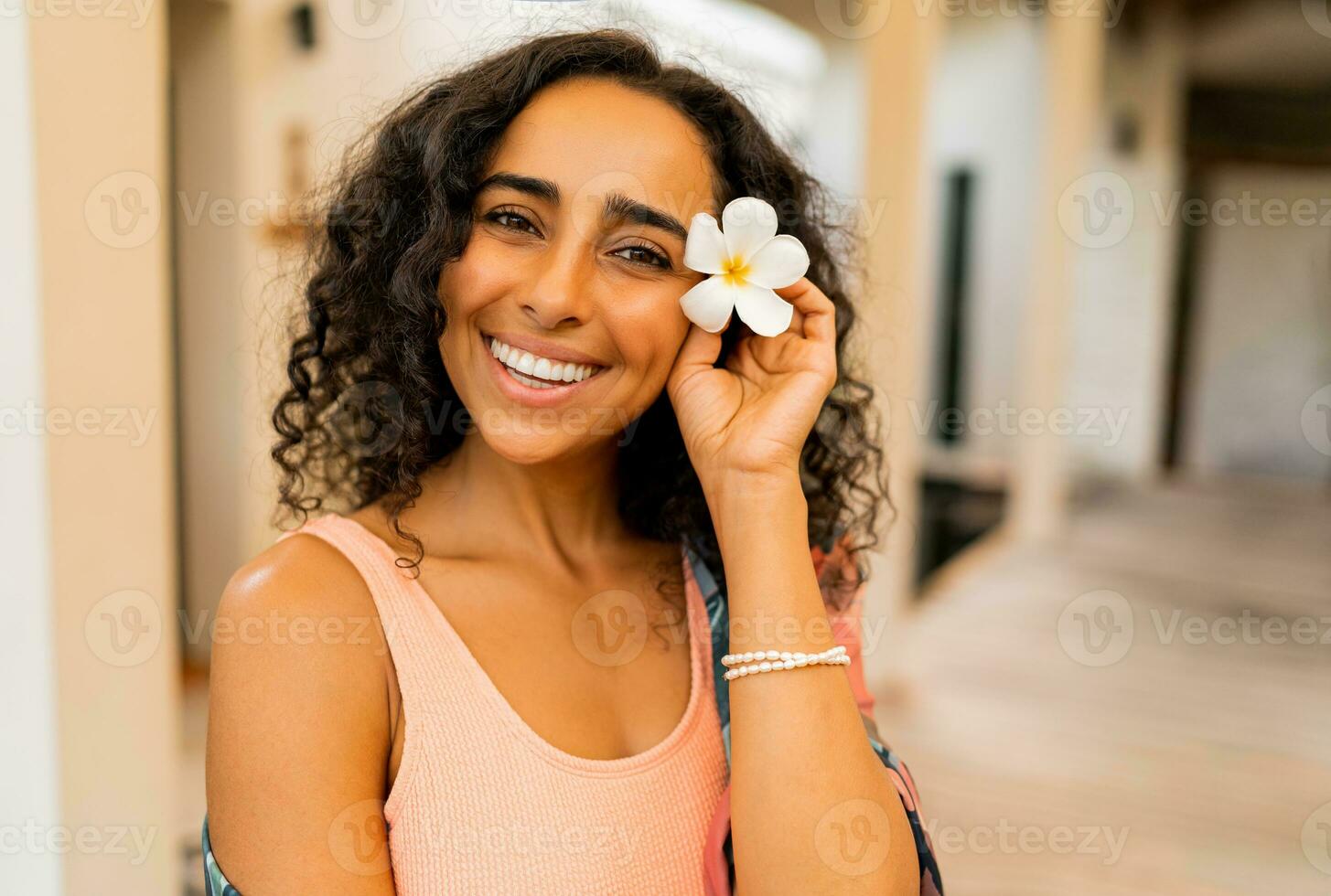 proche en haut portrait de magnifique femme avec tropical fleur dans main posant dans luxe spa Hôtel. spa et corps se soucier concept. photo