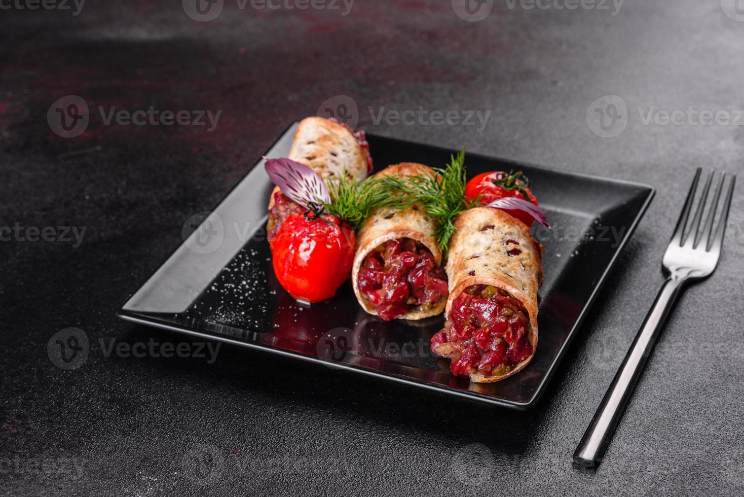 délicieux tartare de boeuf frais avec des toasts sur une plaque carrée noire photo