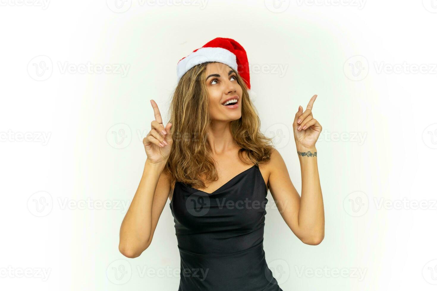 jolie femme dans Père Noël chapeau et relégant noir robe posant sur blanc Contexte dans studio. photo