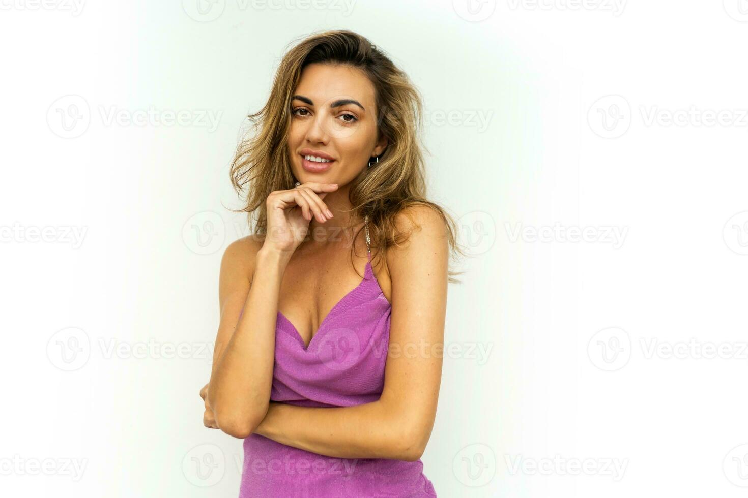 élégant sensuel femme dans élégant brillant rose soir robe posant sur blanc Contexte . ondulé Cheveux, svelte bronzé corps. photo