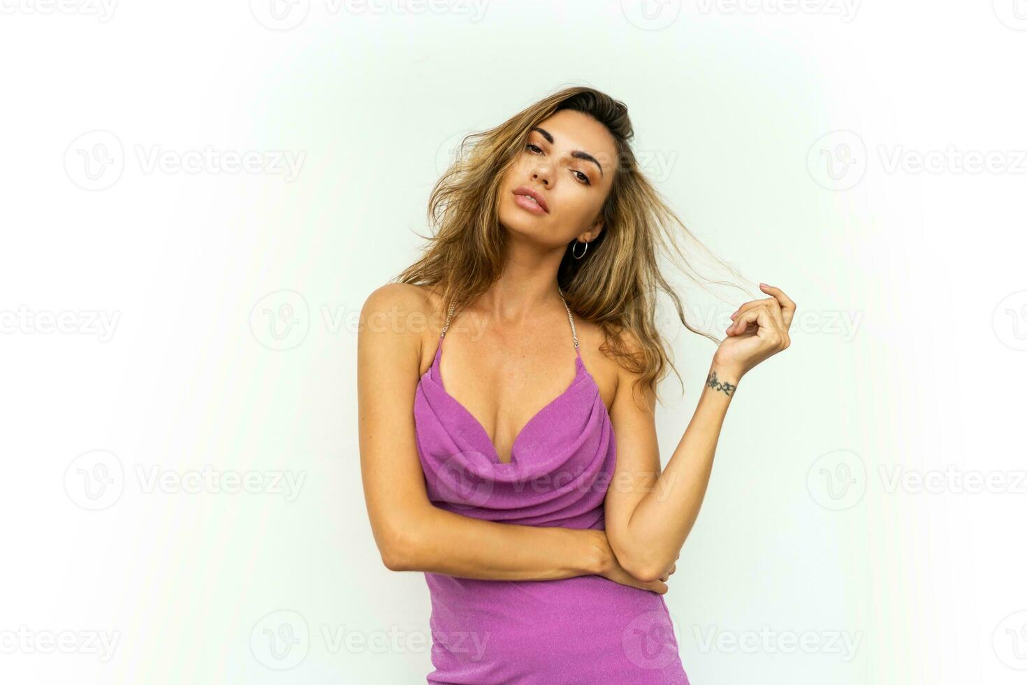 élégant sensuel femme dans élégant brillant rose soir robe posant sur blanc Contexte . ondulé Cheveux, svelte bronzé corps. photo